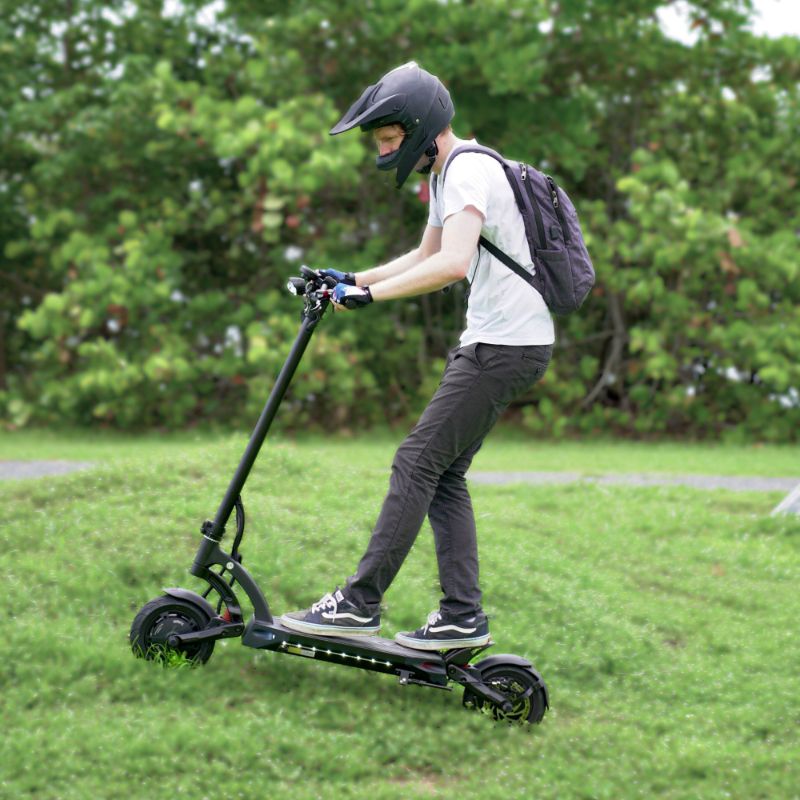 Man in helmet riding up a grass hill on the Mantis 40 MPH electric scooter