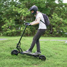 Load image into Gallery viewer, Man in helmet riding up a grass hill on the Mantis 40 MPH electric scooter
