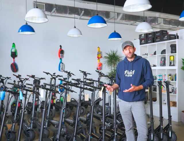 Man in a showroom surrounded by many escooters