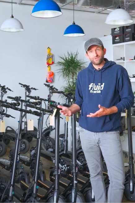 Man in a showroom surrounded by many escooters