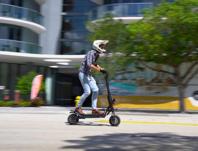Man in helmet riding an electric scooter through town