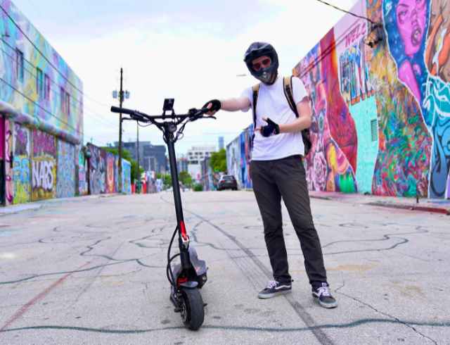 Man in helmet standing next to a fluidfreeride electric scooter