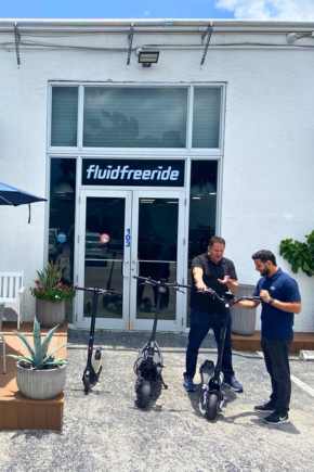 Two men outside of the Miami Showroom standing next to several electric scoooters