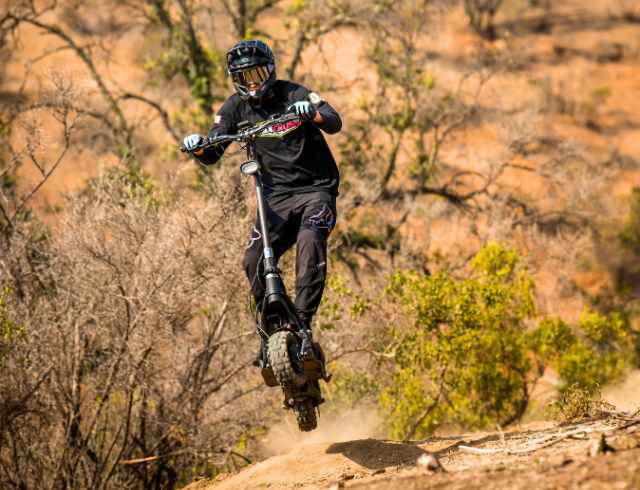 Person in protective gear riding an off road escooter