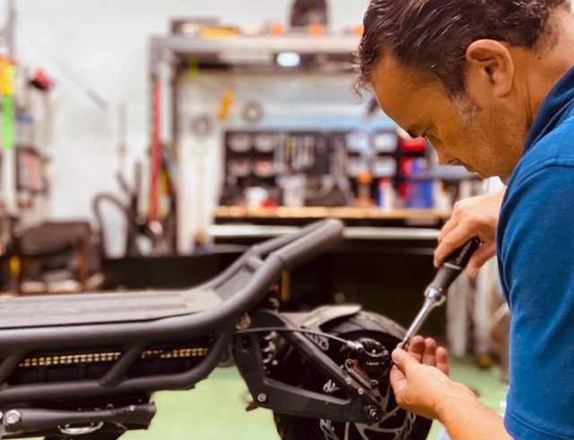 Man using a tool to fix a part on the rear tire of an electric scooter