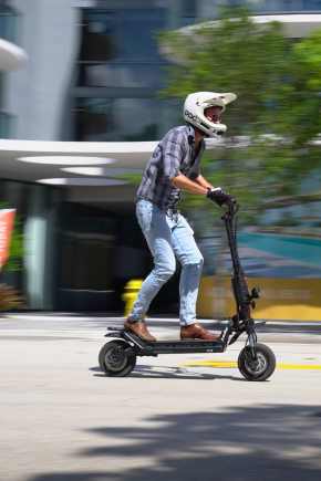 Man in helmet riding an electric scooter through town